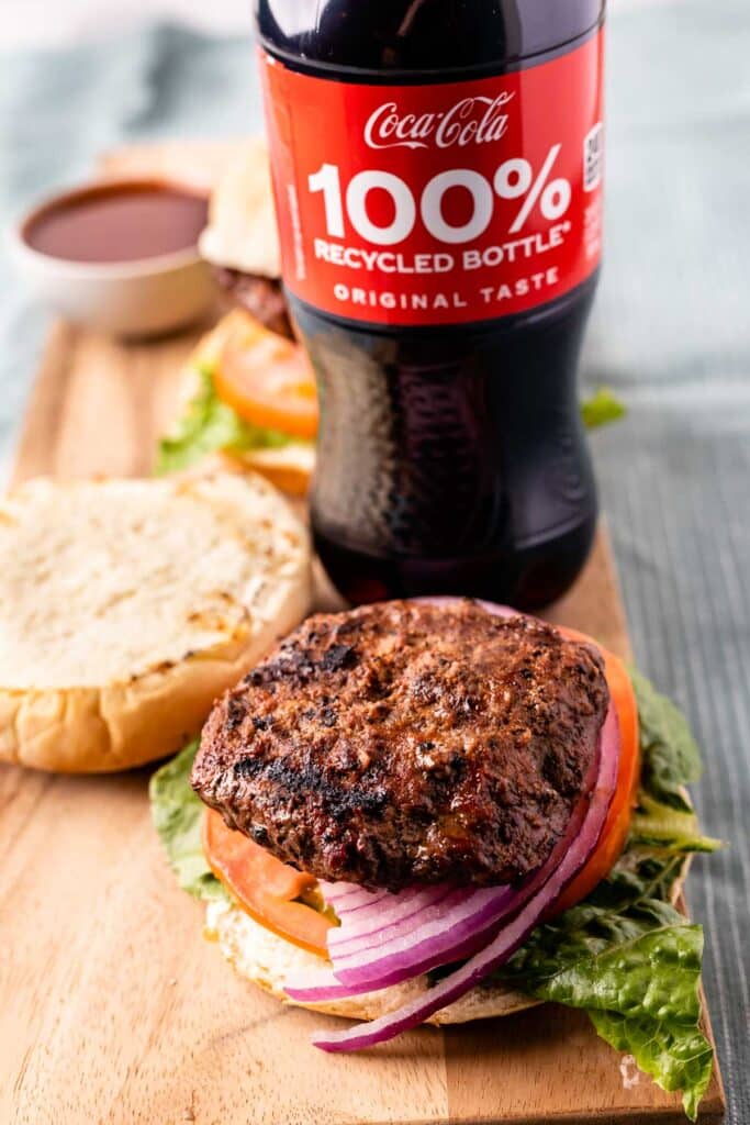 Cola Burger on a cutting board with a coke bottle in the background