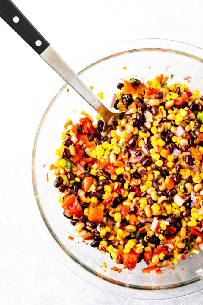 A Clear bowl of cowboy caviar with a big spoon in it