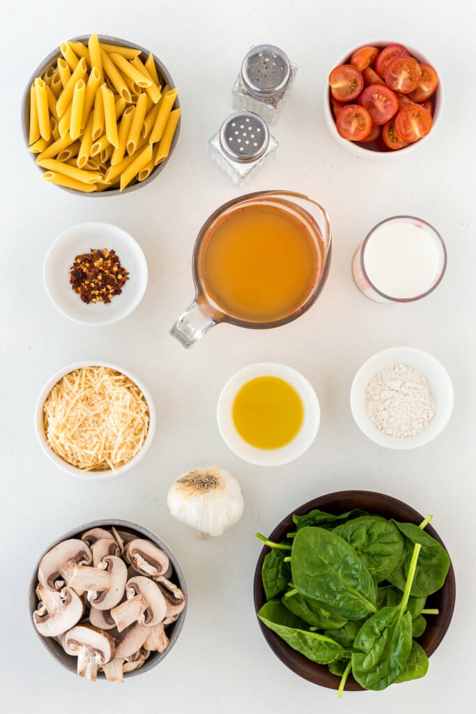 Ingredients to make Mushroom and spinach pasta in bowls and measuring cups