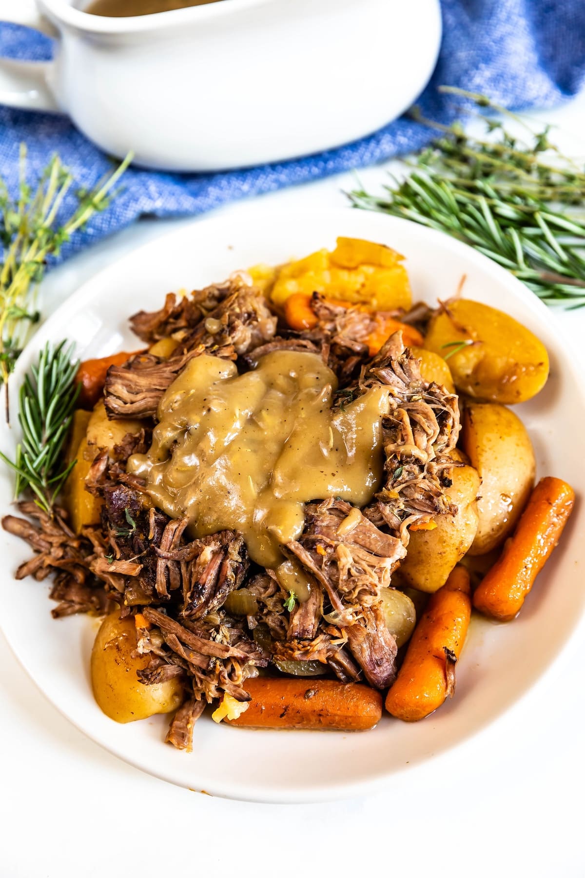 meat on white plate with carrots and gravy.