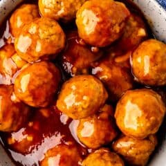 a bowl full of BBQ meatballs all sitting on a blue napkin