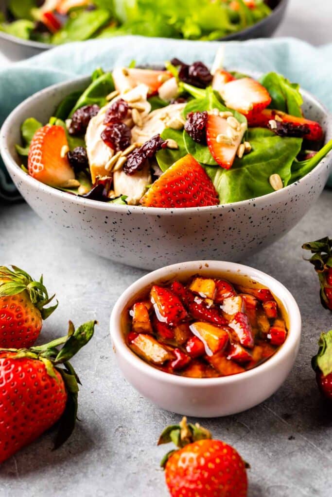 Strawberry chicken salad in a speckled bowl with a small bowl dressing in front