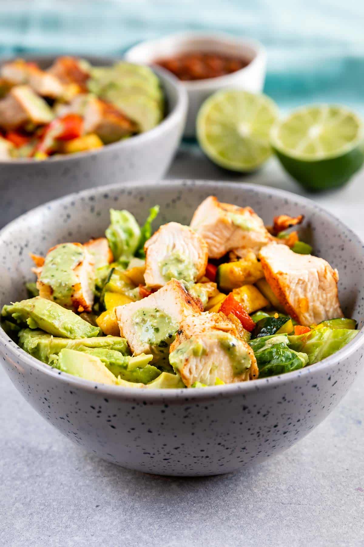 salad and chicken mixed together in a grey spotted bowl.
