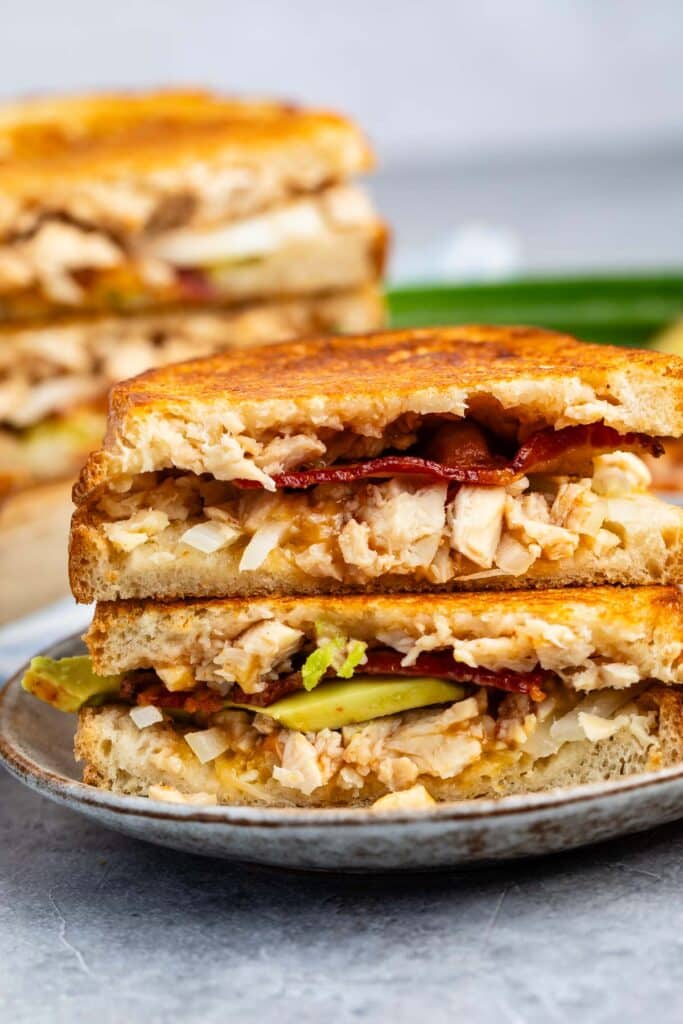 stacked sandwich with chicken and bacon and pickles in the center.