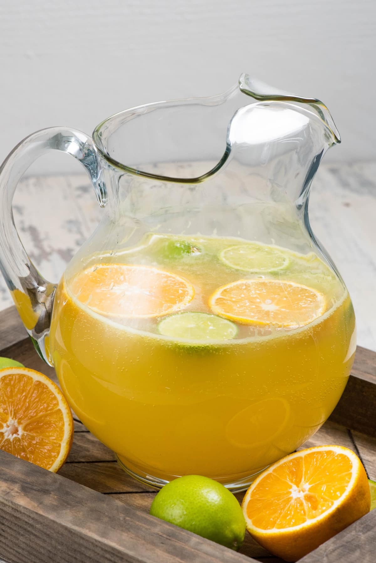 yellow drink with sliced in oranges and limes in a clear glass.