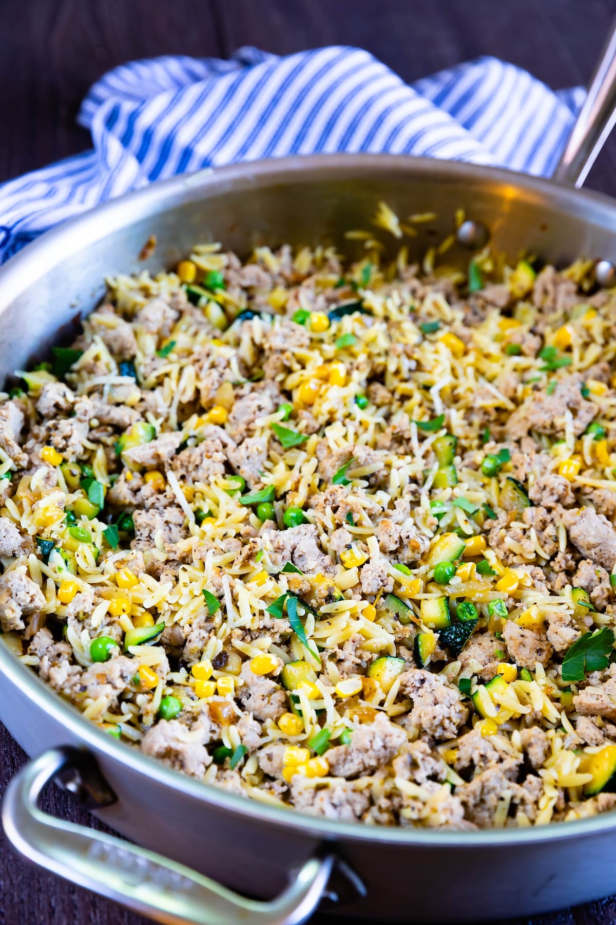 pasta and turkey mixed together with vegetables in a silver skillet.