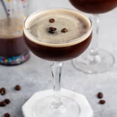 espresso in a tall clear class with coffee beans on top.