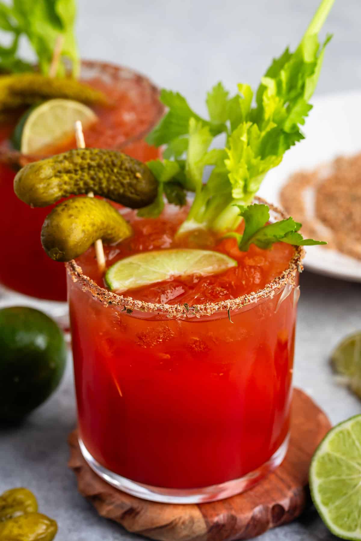 Bloody Mary in a short clear glass with garnish and pickles in the glass.