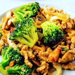 broccoli mixed with onions and mushrooms on a white plate.