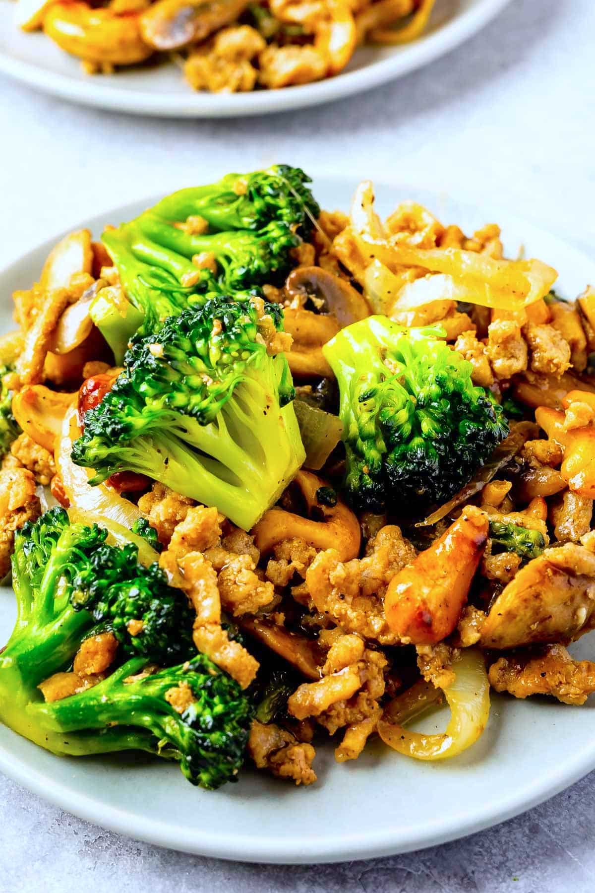 broccoli mixed with onions and mushrooms on a white plate.