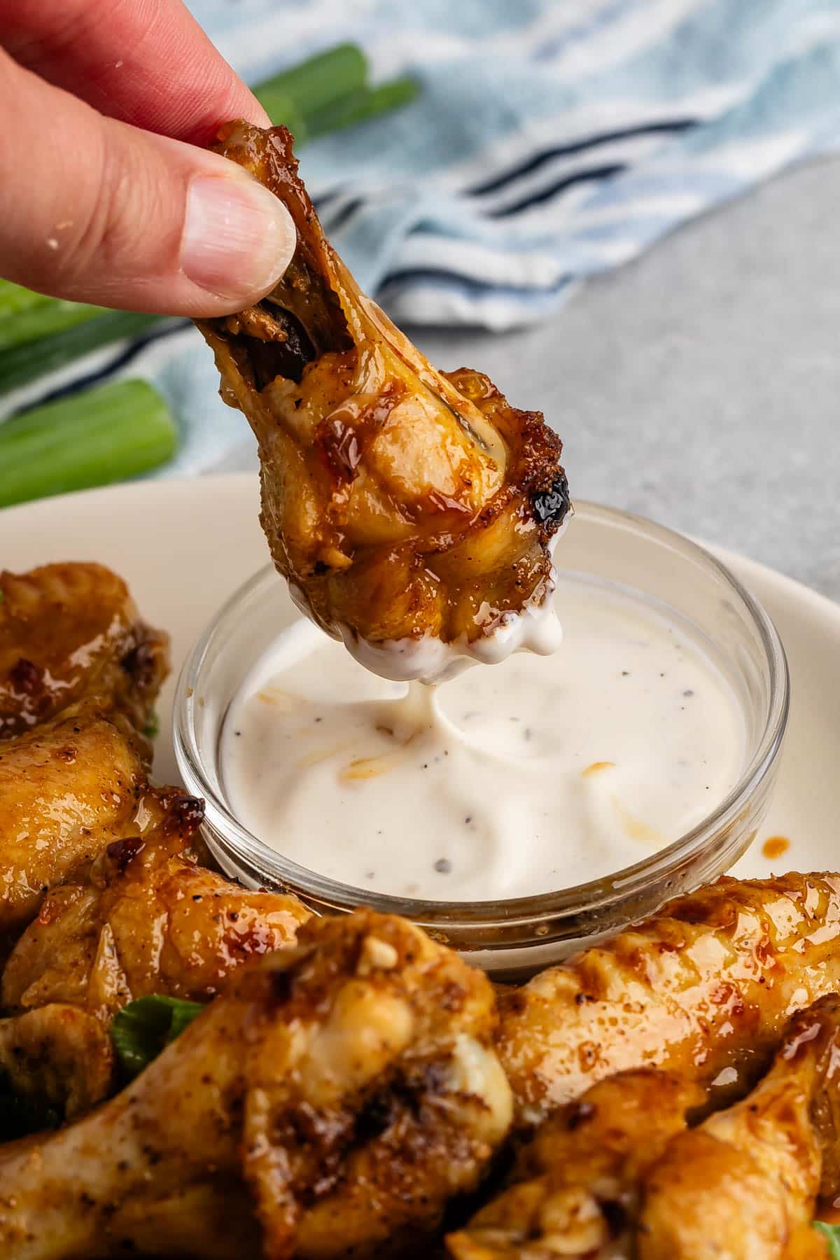 hand holding a chicken wing and dipping it into ranch.