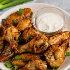 chicken wings on a white plate next to ranch.