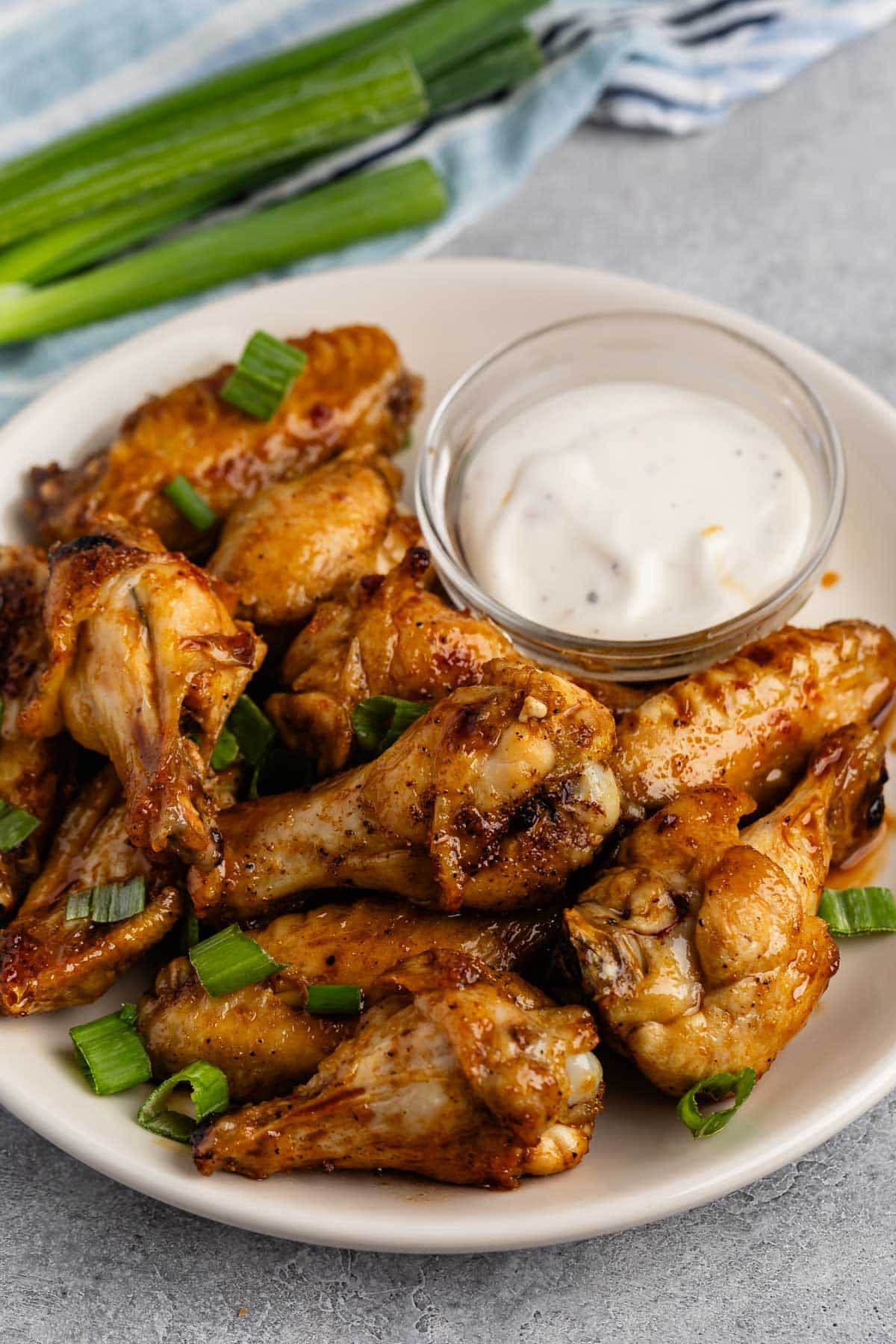 chicken wings on a white plate next to ranch.