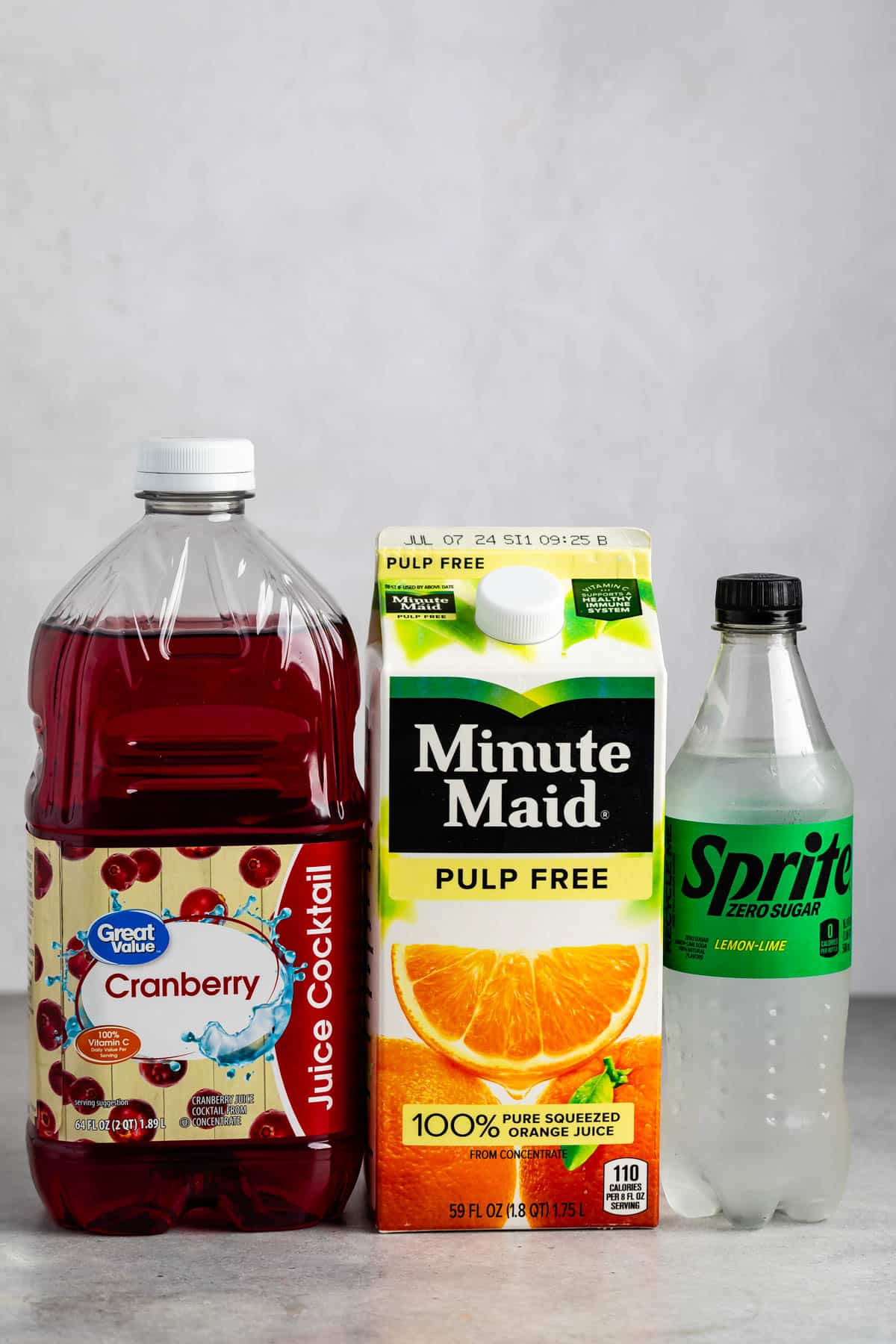 ingredients in cranberry sunrise drink laid out on a grey counter.