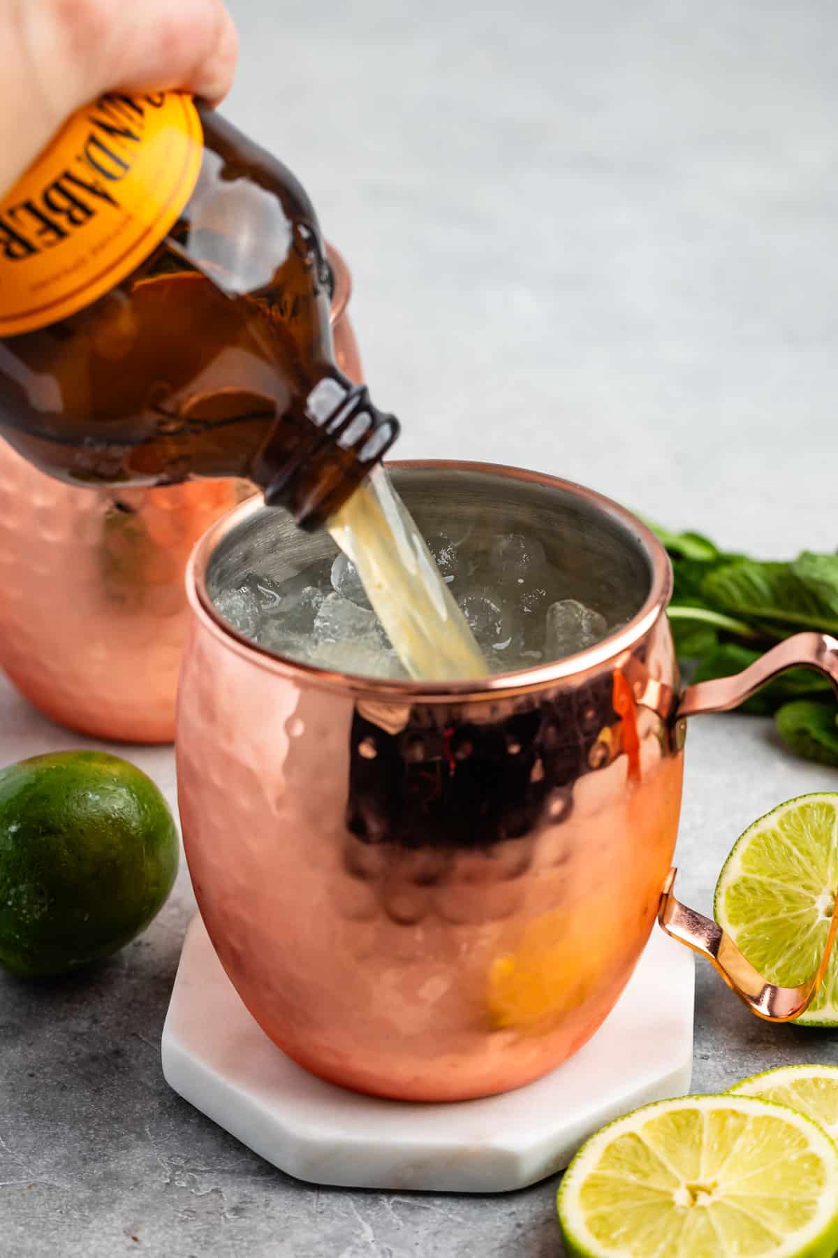 process shot of Moscow mule being poured together in a bronze cup.