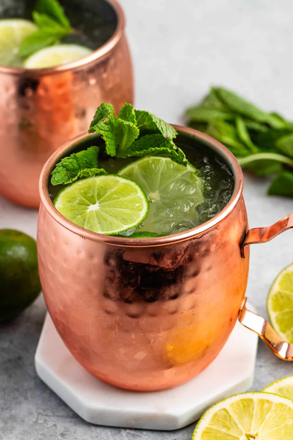 Moscow mule in a bronze cup with sliced limes and garnish in the drink.