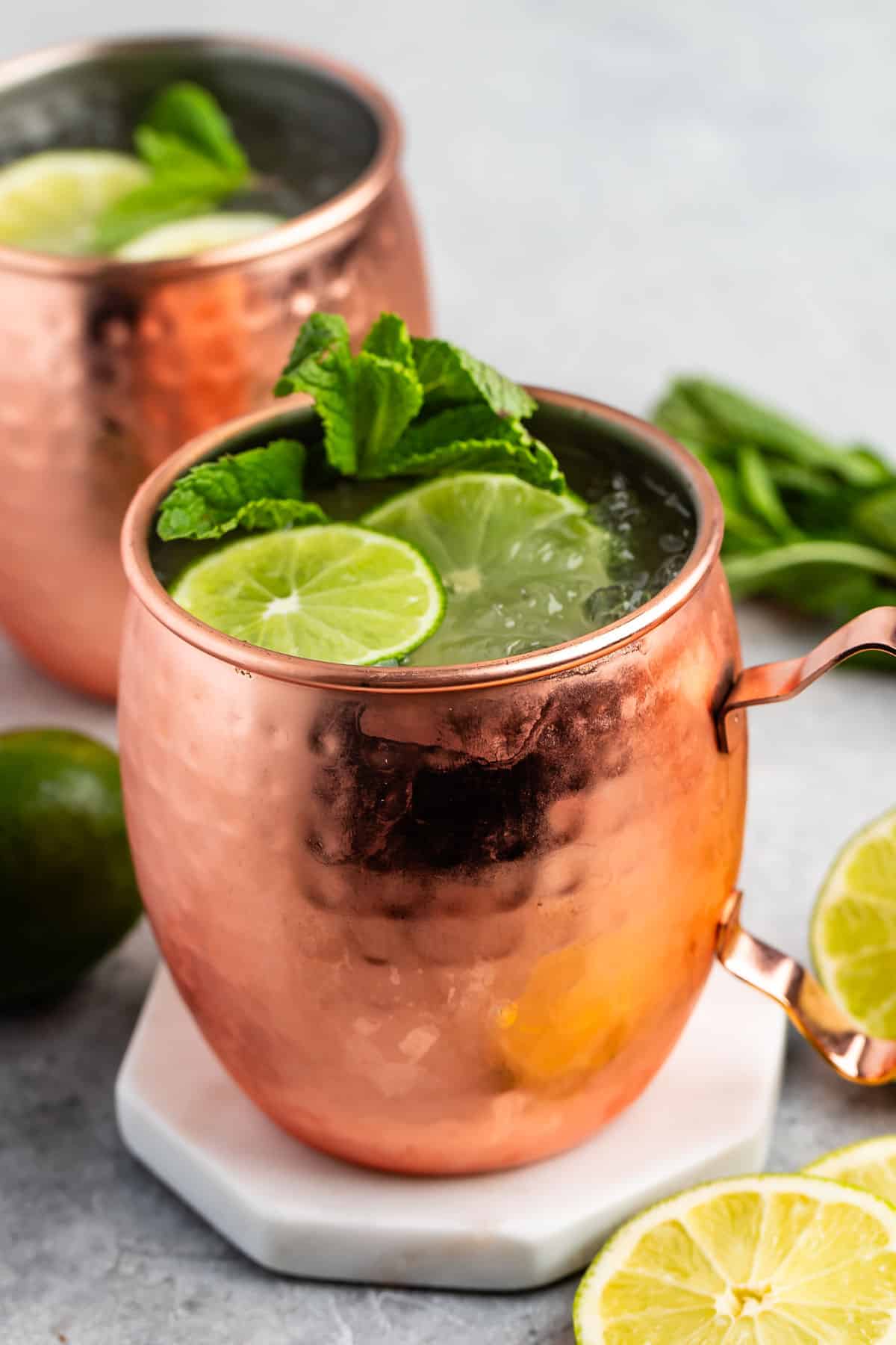 Moscow mule in a bronze cup with sliced limes and garnish in the drink.