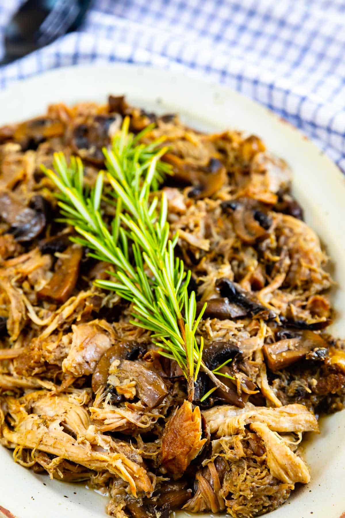 pulled pork on white plate with rosemary.