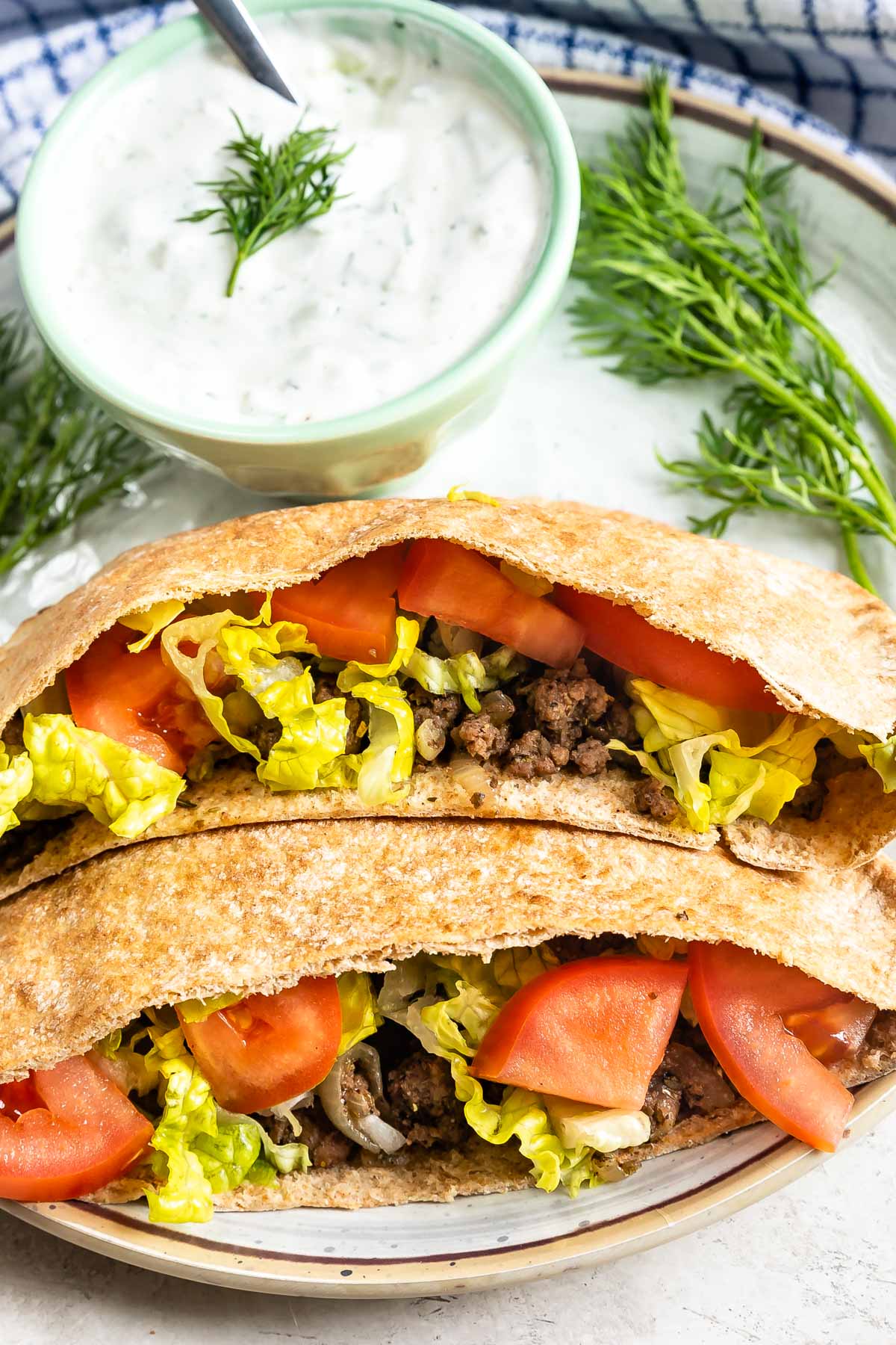 ground beef gyro stuffed in pita pockets on a white plate.