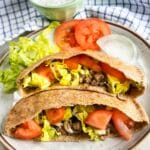 ground beef gyro stuffed in pita pockets on a white plate.