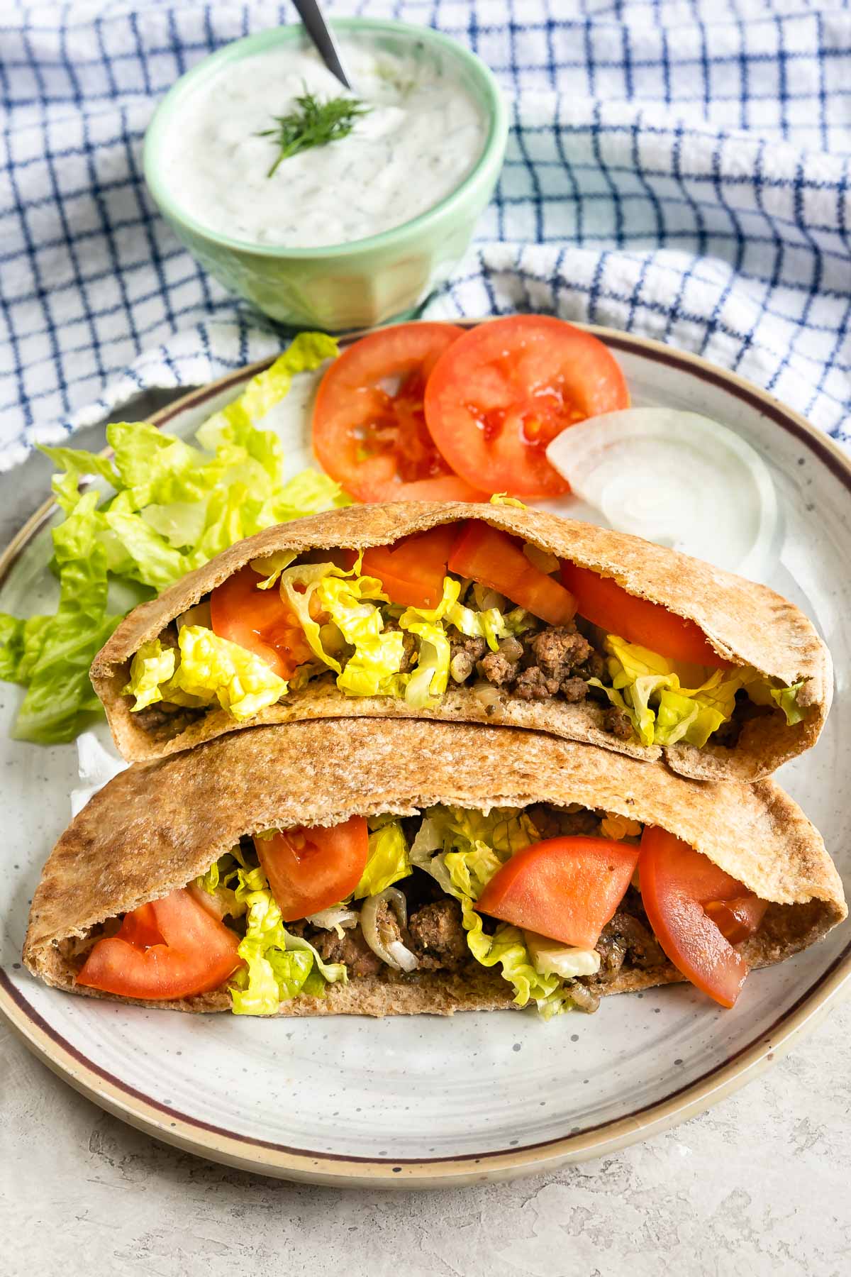 ground beef gyro stuffed in pita pockets on a white plate.