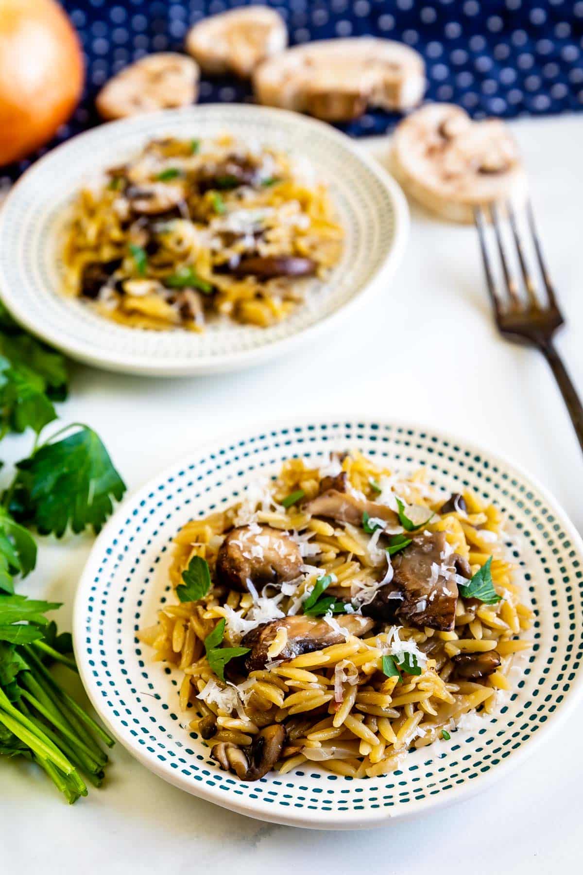 orzo laid out on a spotted white plate with mushrooms.