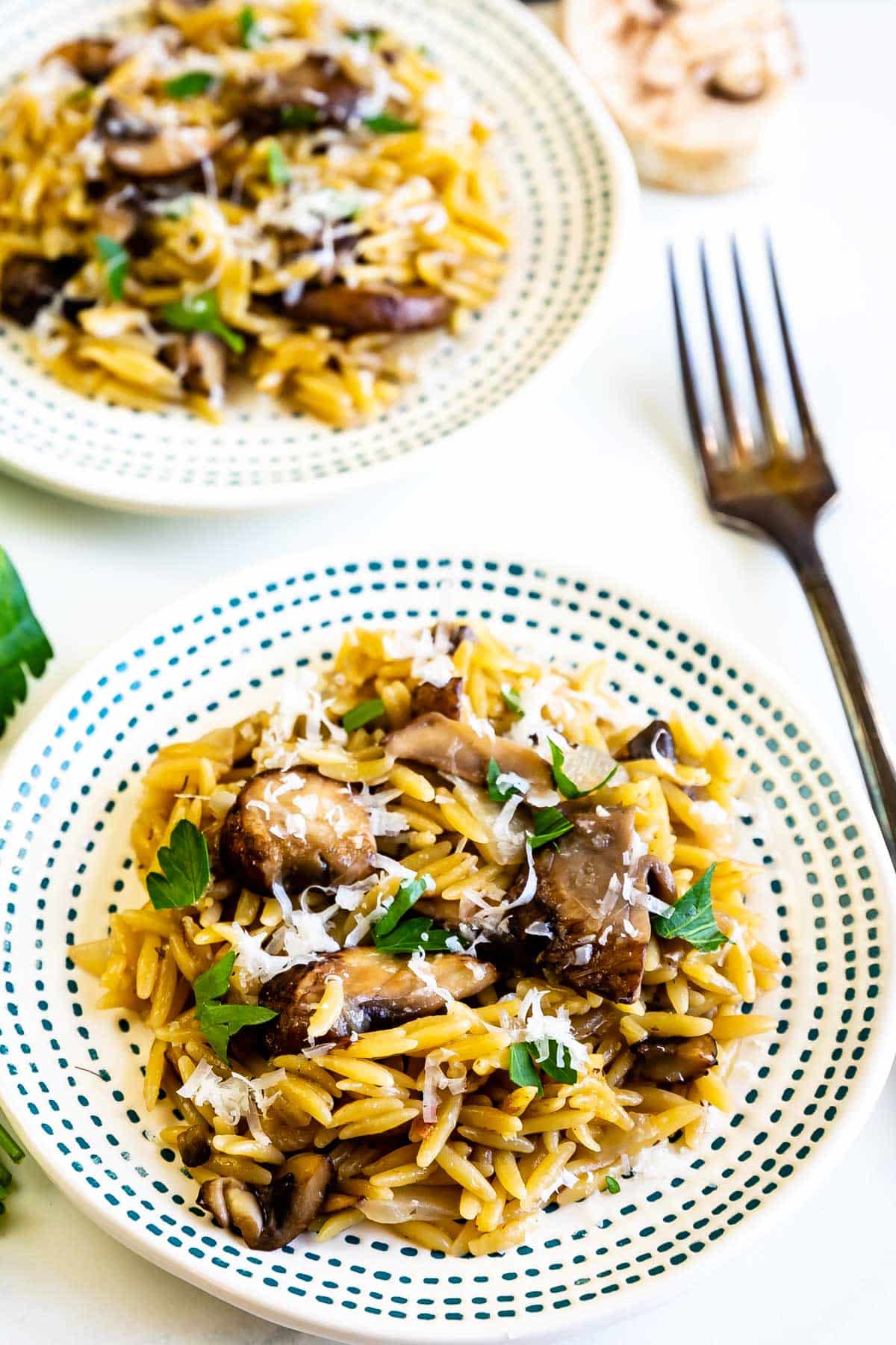 orzo laid out on a spotted white plate with mushrooms.