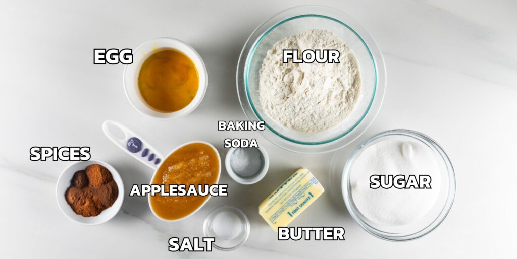 ingredients in applesauce cake laid out on a white marble counter.