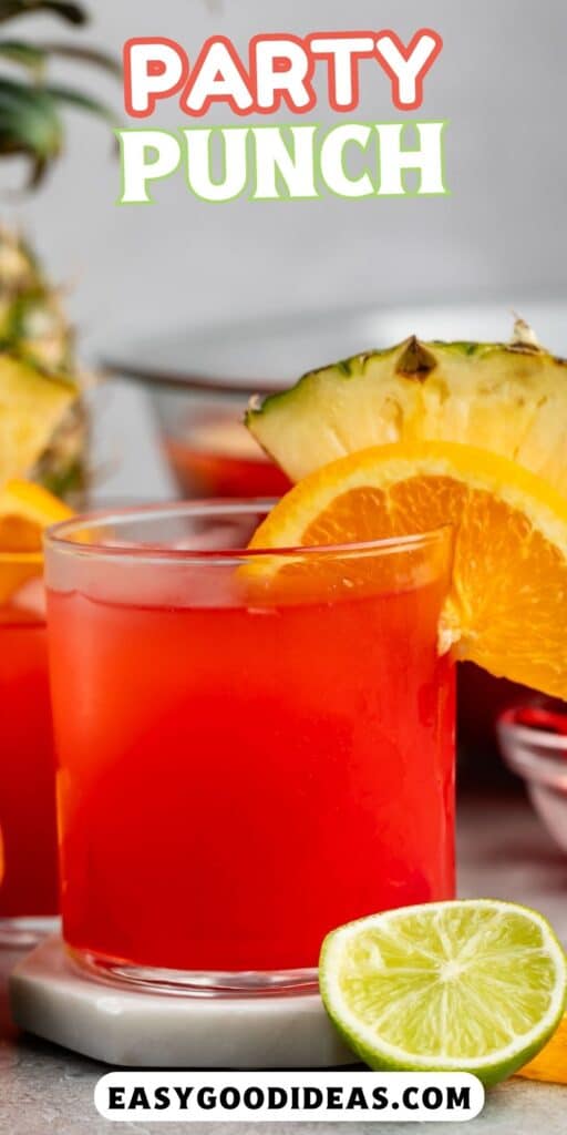 short clear glass with red drink inside and an orange and pineapple slice on the rim with words on the image.