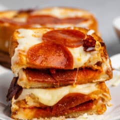 stacked grilled cheese with pepperoni baked on top and inside the sandwich.