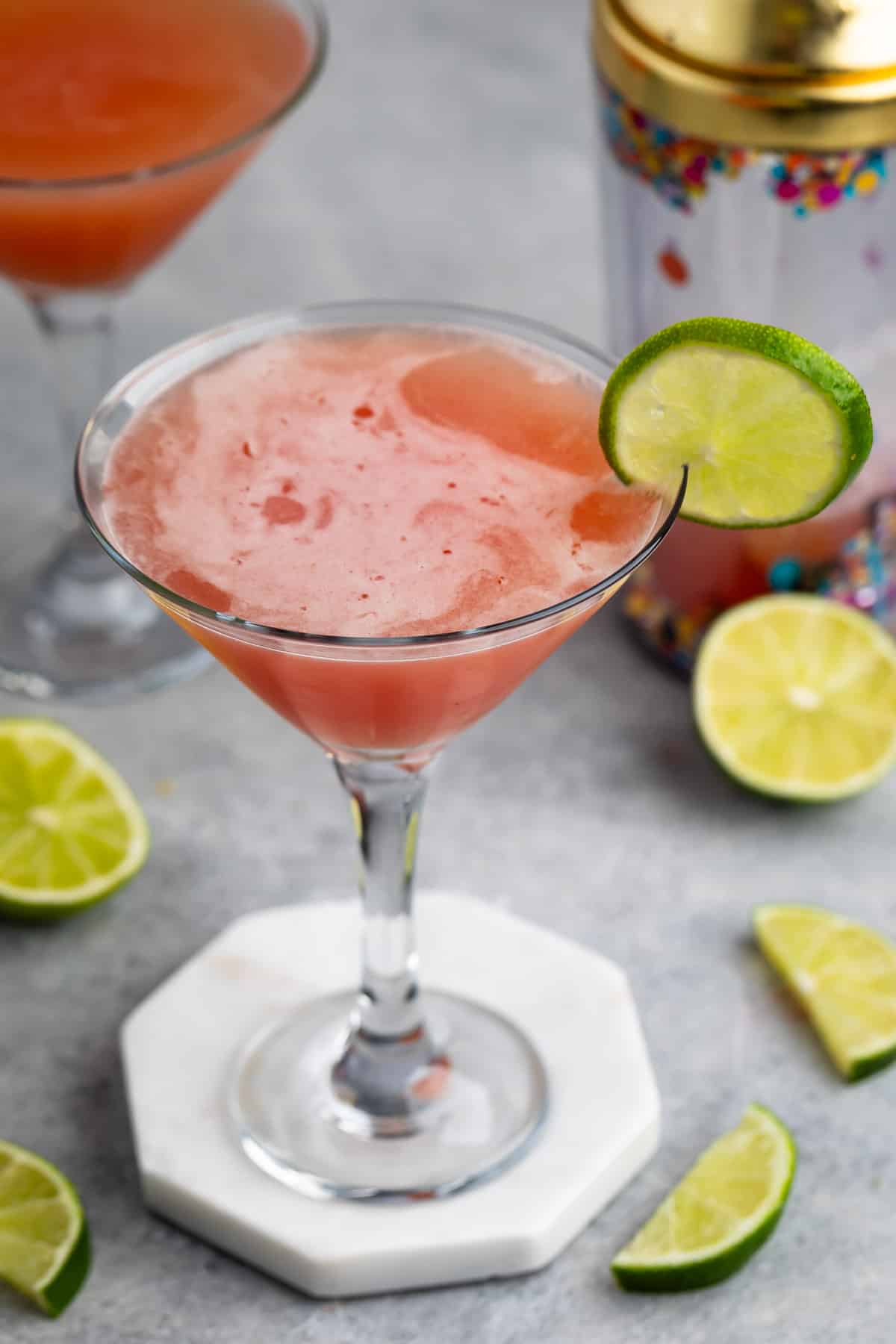 wine glass filled with orange drink with lime on the rim.