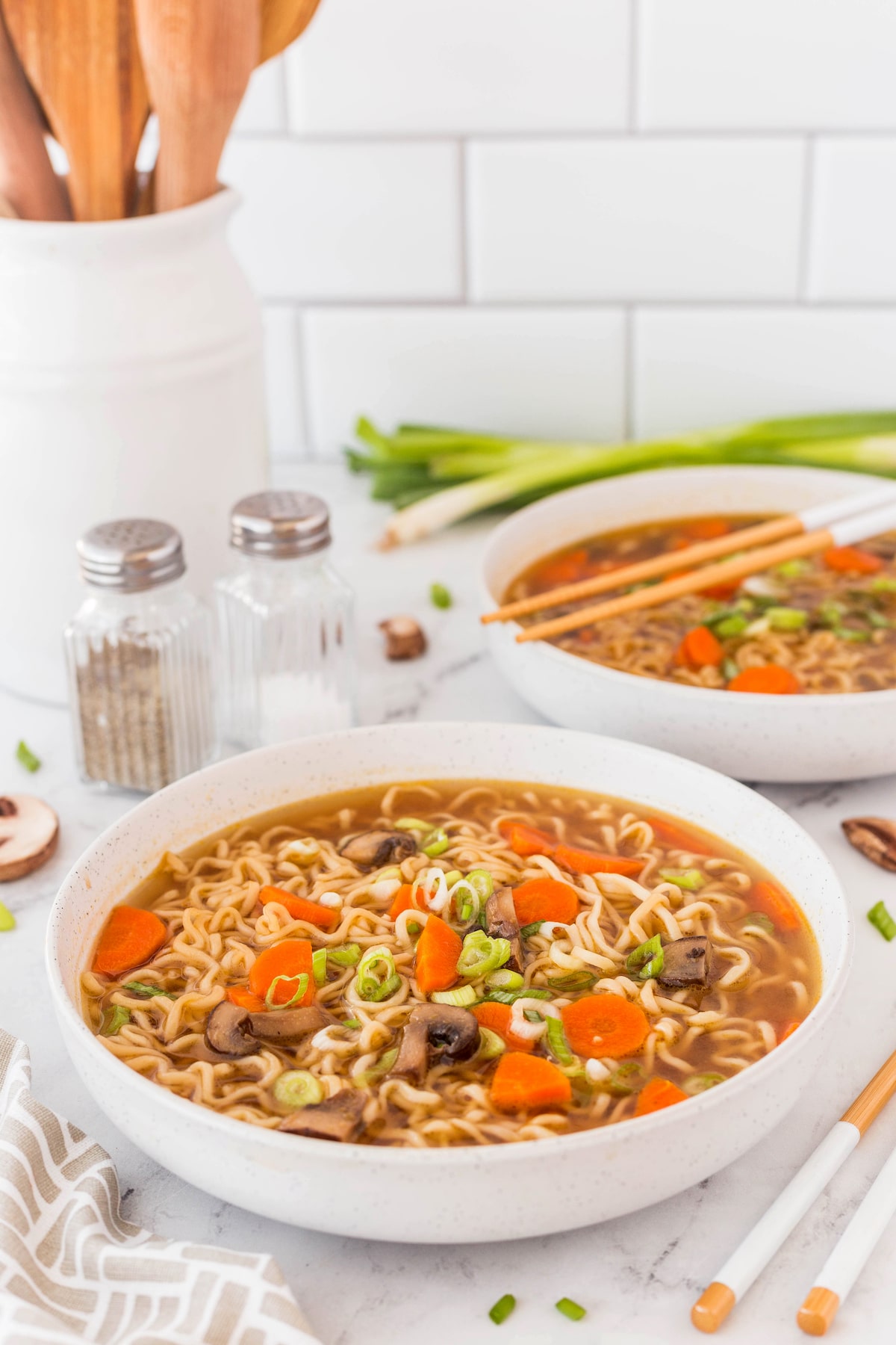 ramen in a large whole bowl topped with carrots and mushrooms and green onions.