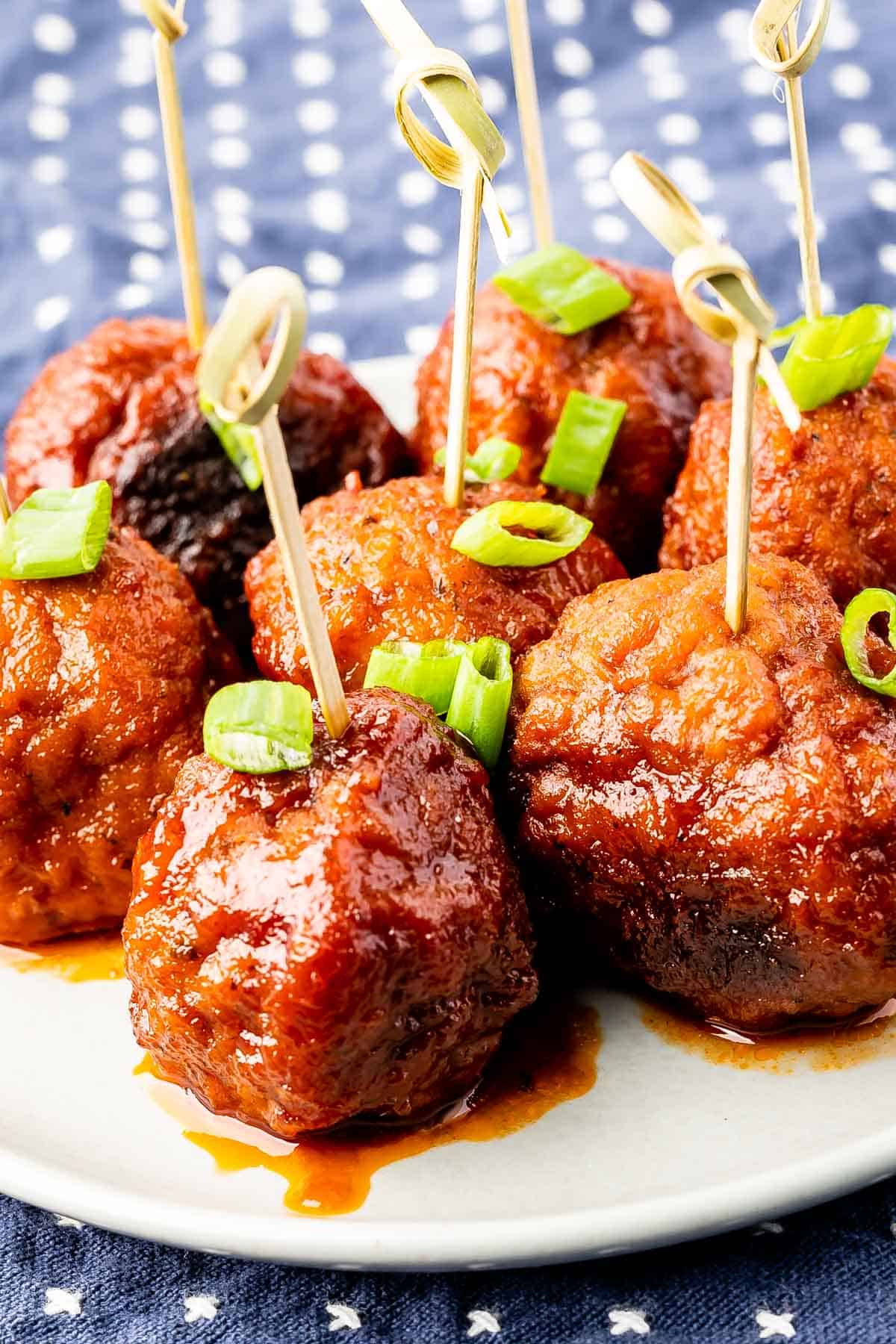 meatballs on a white plate covered in sauce with sticks in the top.