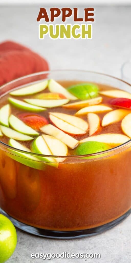 apple punch in a large clear bowl with sliced apples on top.