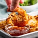 hand holding shrimp on a pan next to a sauce.