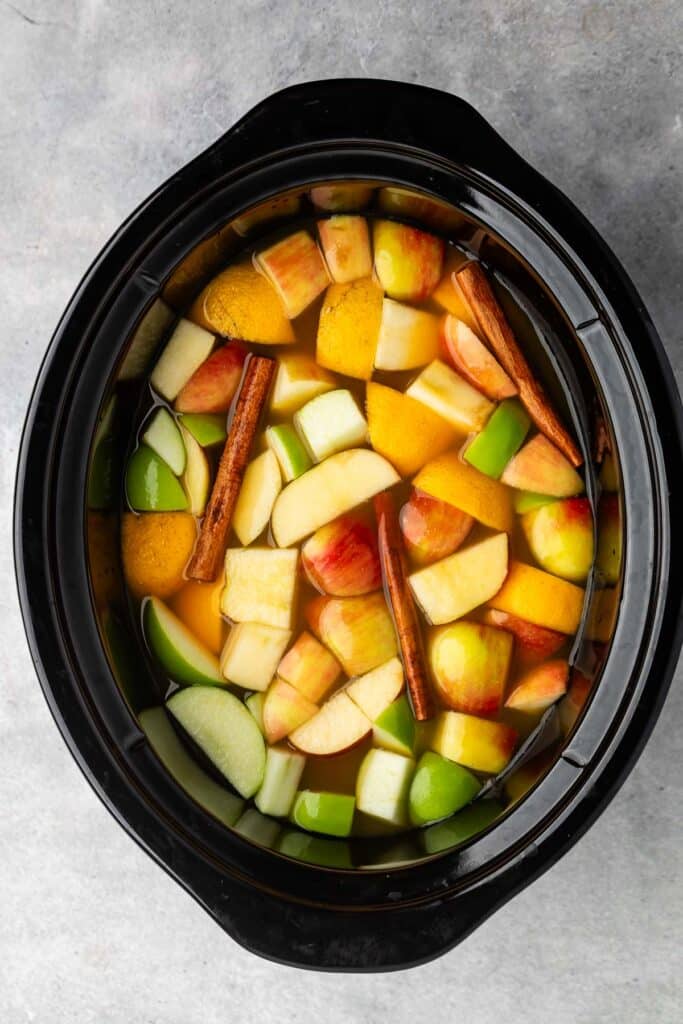 apple cider mixed with apples and cinnamon sticks and orange slices.