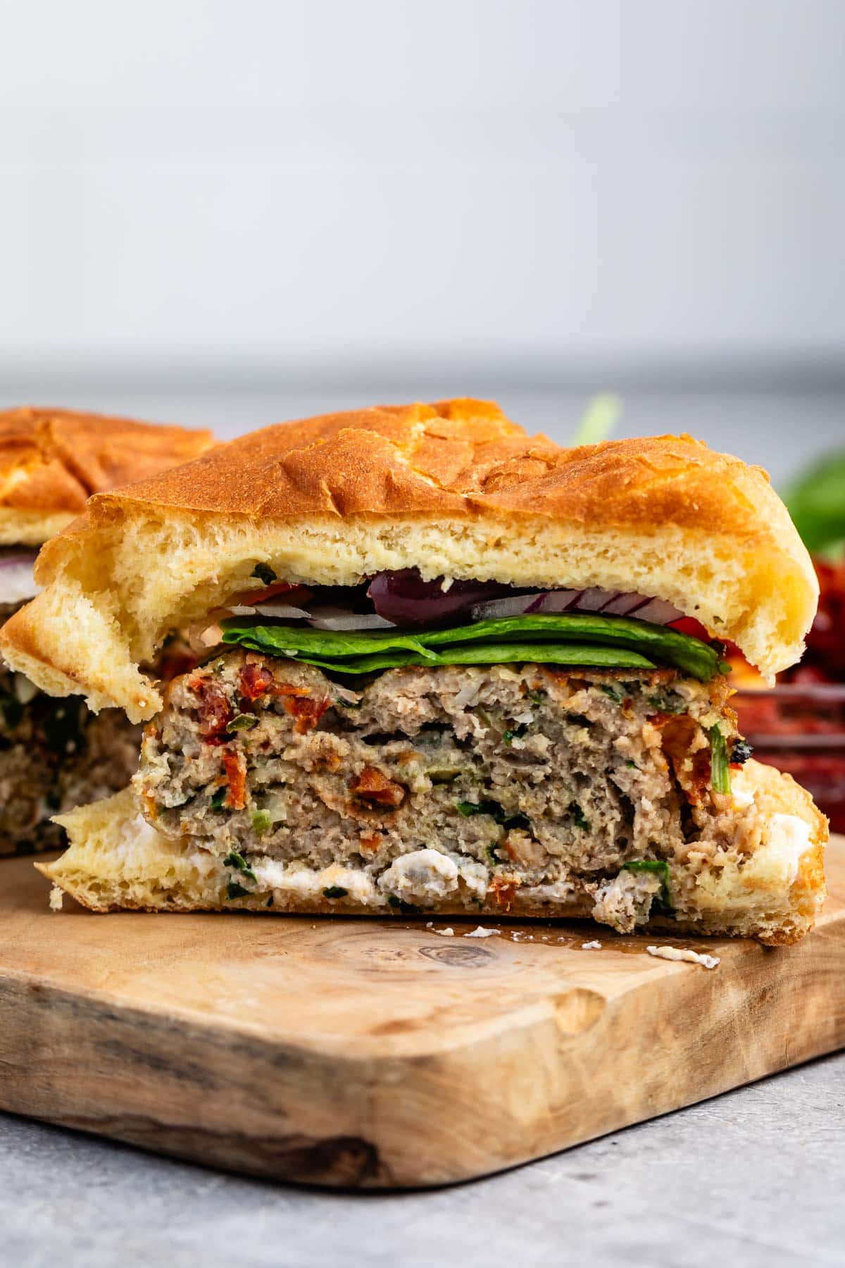 turkey burger on a cutting board with many toppings and buns cut in half.