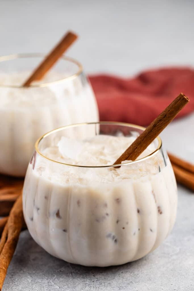 White Russian with a cinnamon stick laying inside a pumpkin shaped glass.