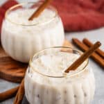 White Russian with a cinnamon stick laying inside a pumpkin shaped glass.