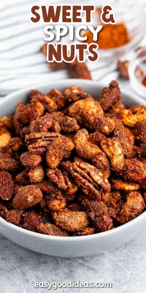 A bowl filled with mixed nuts coated in a sweet and spicy seasoning. The text above reads Sweet & Spicy Nuts and at the bottom, easygoodideas.com. The background includes ingredients in small bowls.