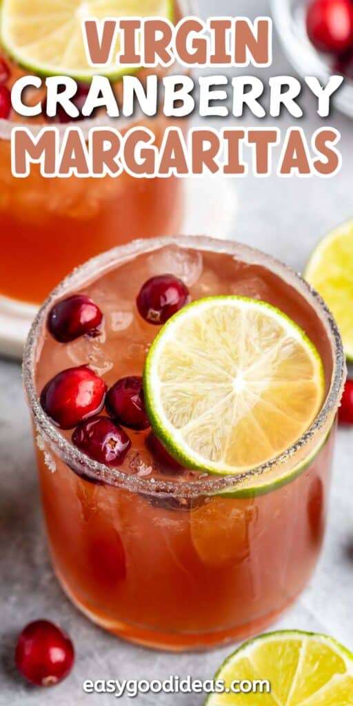 A glass of virgin cranberry margarita garnished with slices of lime and fresh cranberries. The rim is coated with salt. Another similar drink and lime slices are in the background. Text on the image reads Virgin Cranberry Margaritas.