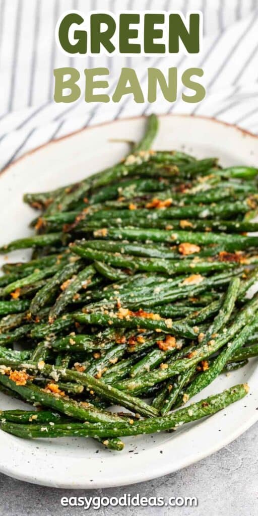 A plate of roasted green beans topped with grated cheese and spices is placed on a white dish. The background shows a striped cloth. The words GREEN BEANS are written at the top, and easygoodideas.com is at the bottom.