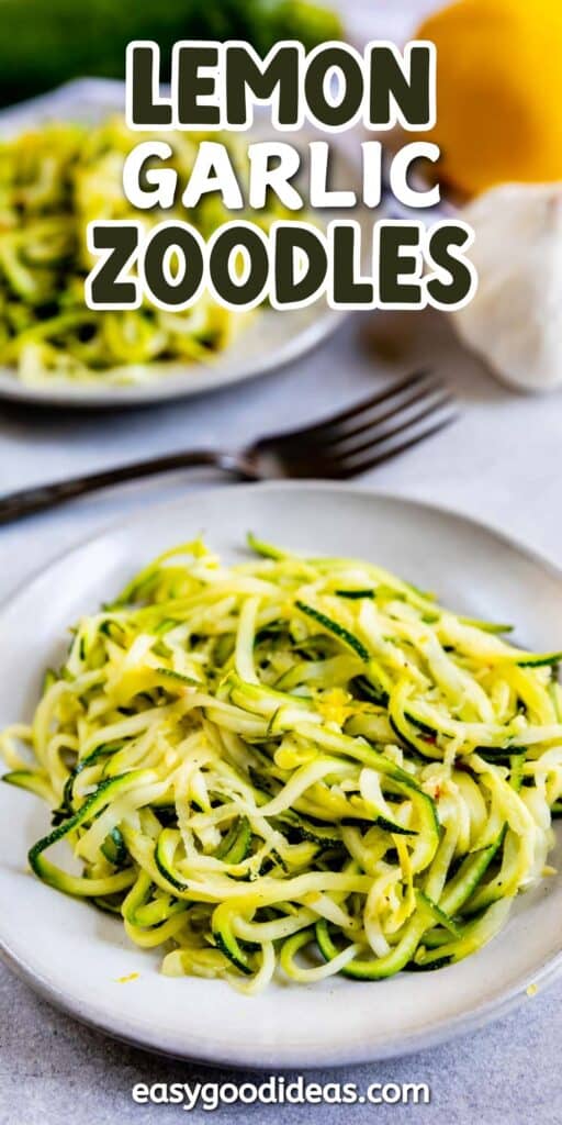 A plate of zucchini noodles, known as zoodles, is served with lemon and garlic seasoning. In the background, another plate with zoodles and a fork are visible. The text reads Lemon Garlic Zoodles with a website link below.