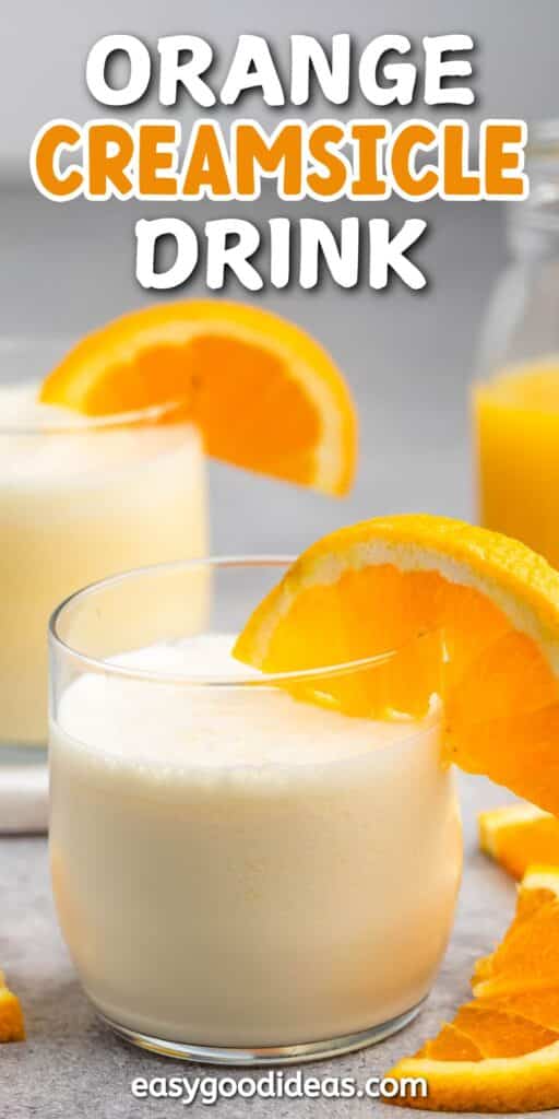 A creamy orange drink in a glass, garnished with an orange slice. In the background, theres another glass of the drink and a jug filled with the same beverage. Text at the top reads Orange Creamsicle Drink.