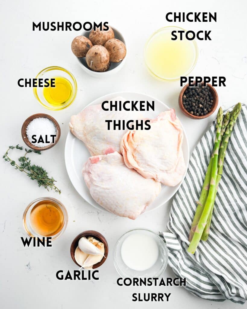 Ingredients for a recipe are laid out on a surface. Items include chicken thighs, mushrooms, chicken stock, cheese, pepper, asparagus, cornstarch slurry, garlic, wine, salt, and fresh thyme. A striped cloth is visible on the side.