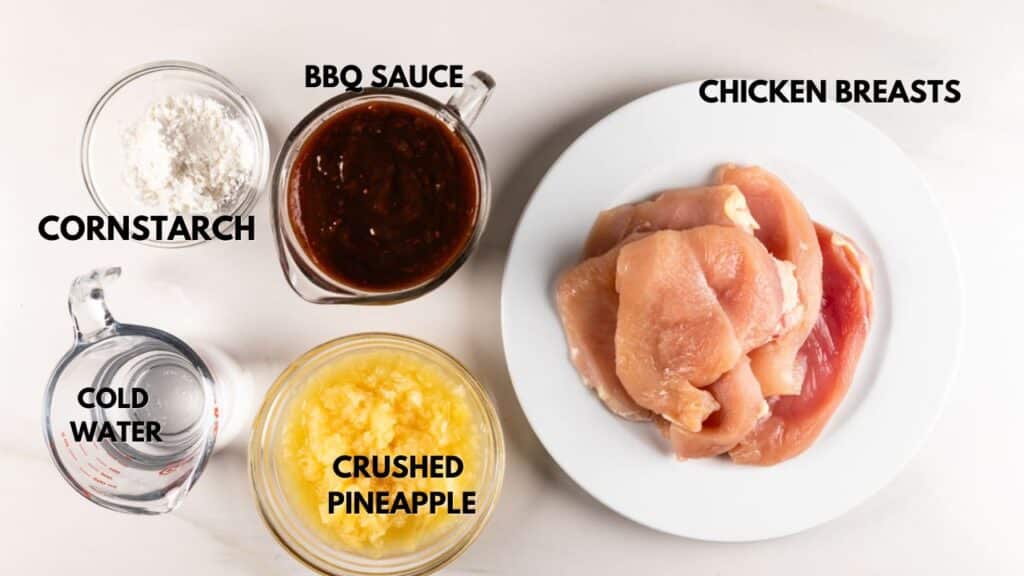 Top-down view of ingredients on a white surface: raw chicken breasts on a plate, bowls of BBQ sauce, crushed pineapple, cornstarch, and a measuring cup with cold water. Labels identify each item.