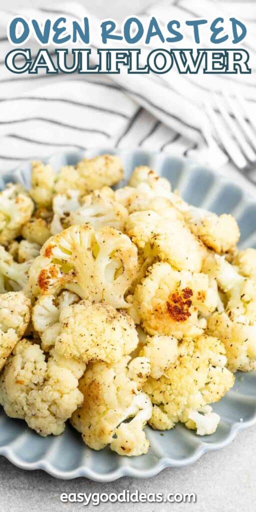 A plate of oven-roasted cauliflower florets seasoned with herbs, served on a light blue dish. The background shows a striped cloth.