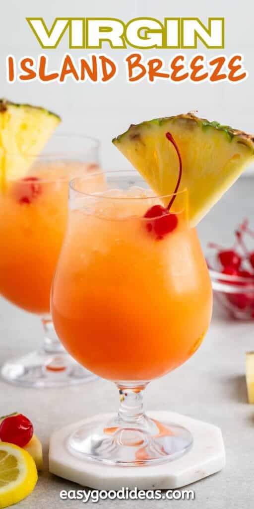 Two tropical cocktails with orange liquid, served in curvy glasses. Each drink is garnished with a pineapple slice and a cherry. Additional cherries are scattered on the surface, and Virgin Island Breeze text is at the top.
