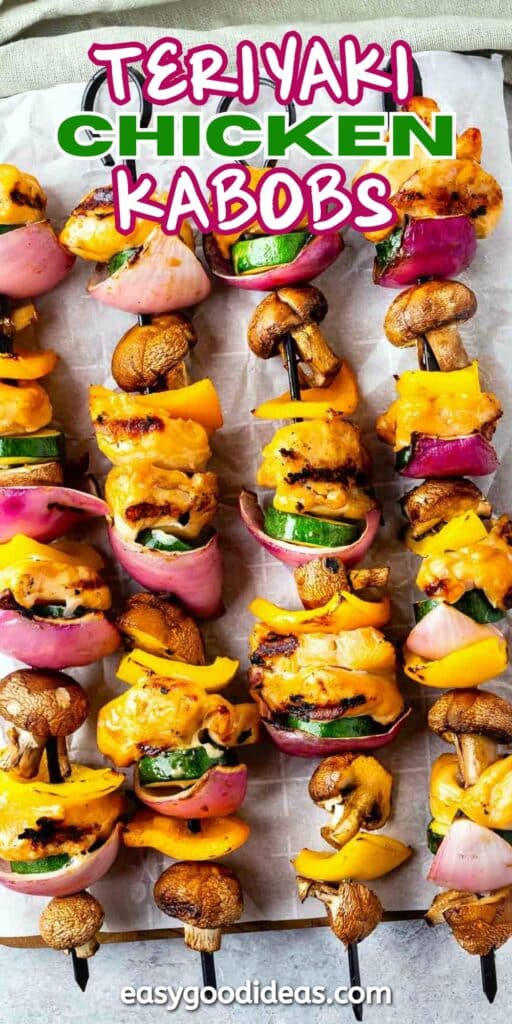 Skewers of grilled teriyaki chicken, bell peppers, red onion, zucchini, and mushrooms are arranged on parchment paper. Bright colors and a text overlay read Teriyaki Chicken Kabobs with additional text at the bottom.