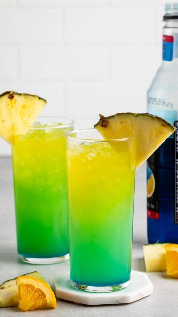 yellow and green drink with a pineapple slice on the rim.